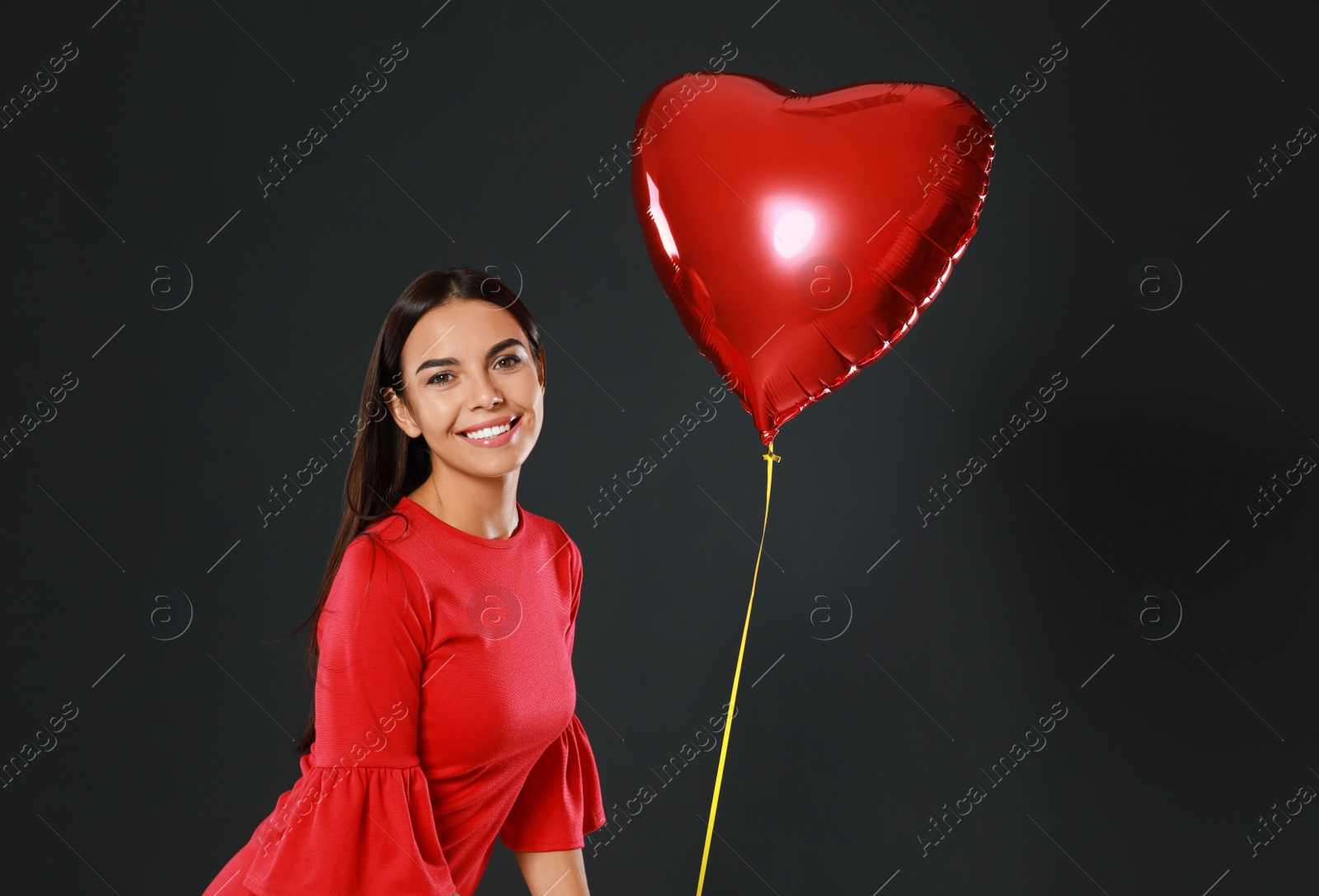 Photo of Beautiful woman with heart shaped balloon on dark background