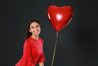 Photo of Beautiful woman with heart shaped balloon on dark background