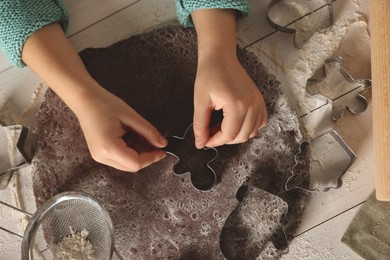 Photo of Little child making Christmas cookies at white wooden table, top view