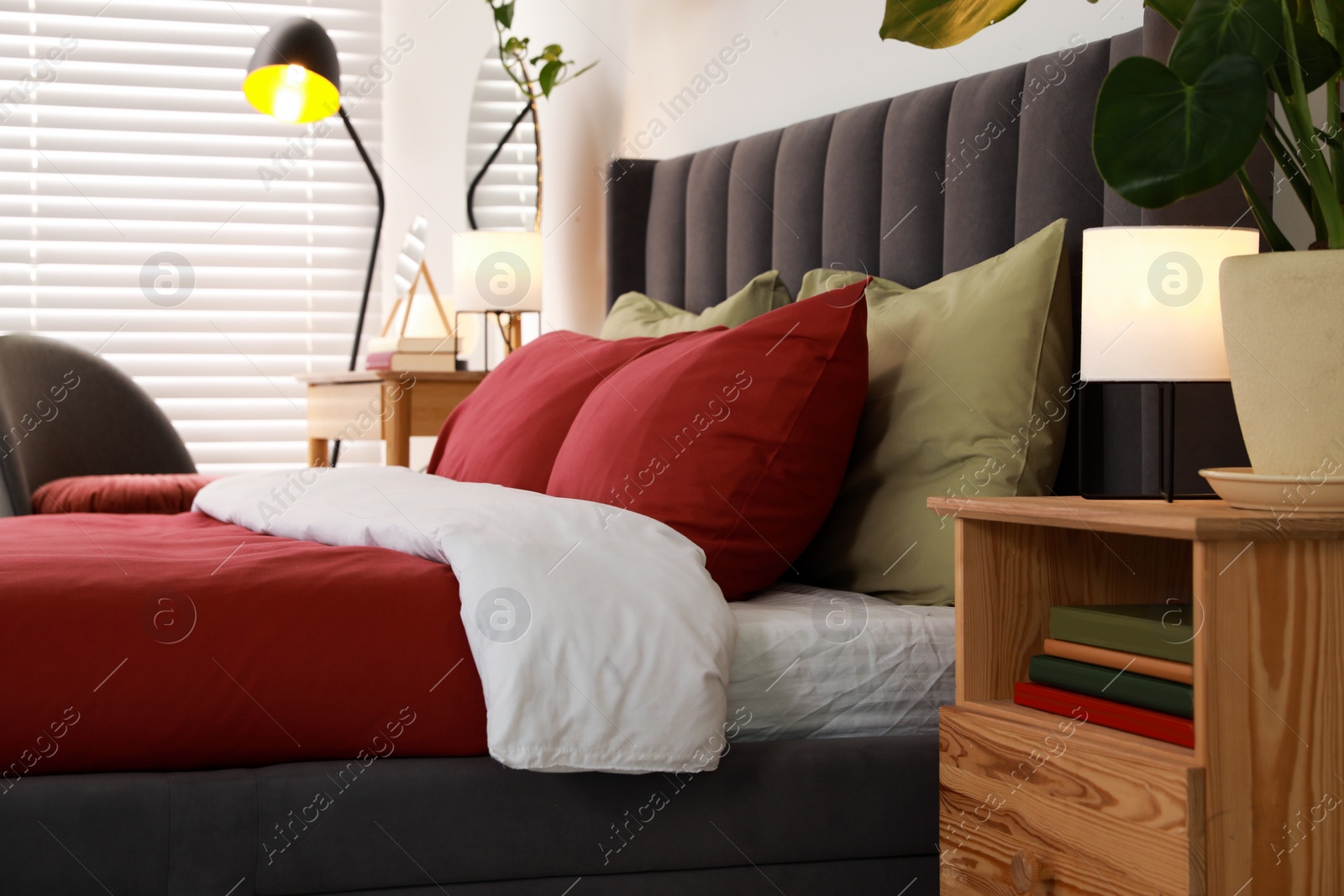 Photo of Stylish bedroom interior with comfortable bed, nightstand and green houseplant