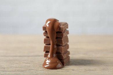 Photo of Pieces of milk chocolate with tasty paste on wooden table, closeup
