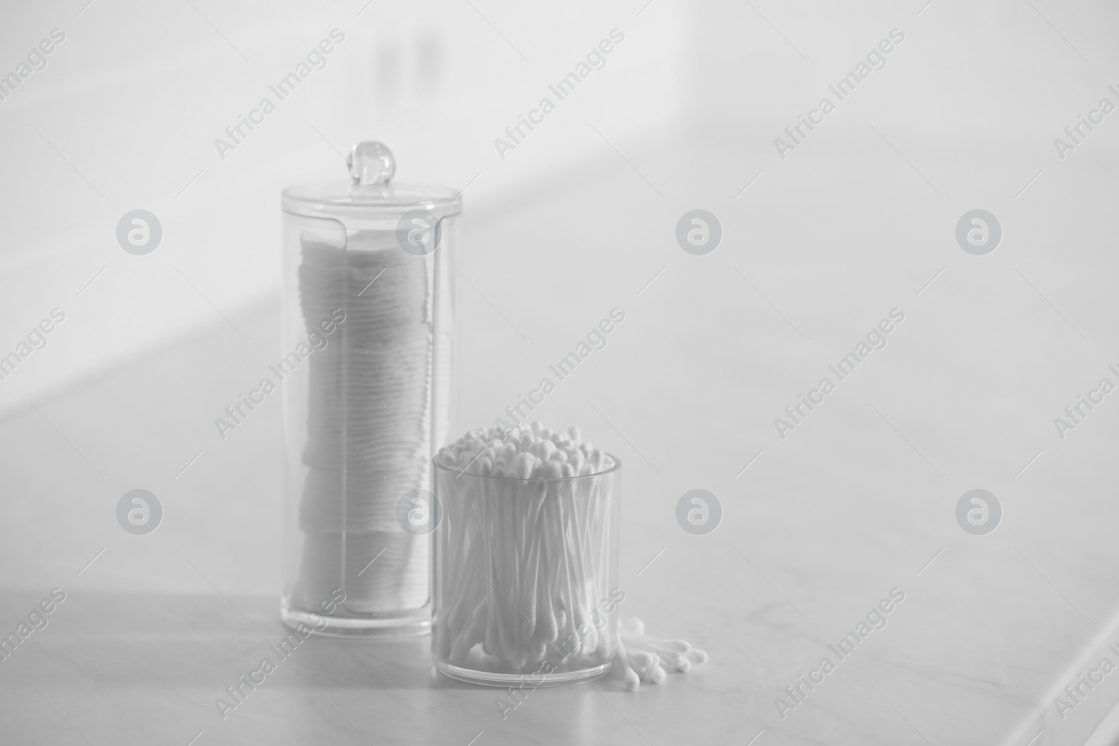 Photo of Cotton buds and pads in transparent holders on light table, space for text