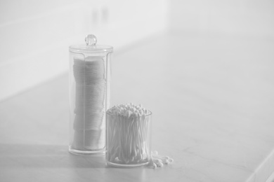 Photo of Cotton buds and pads in transparent holders on light table, space for text