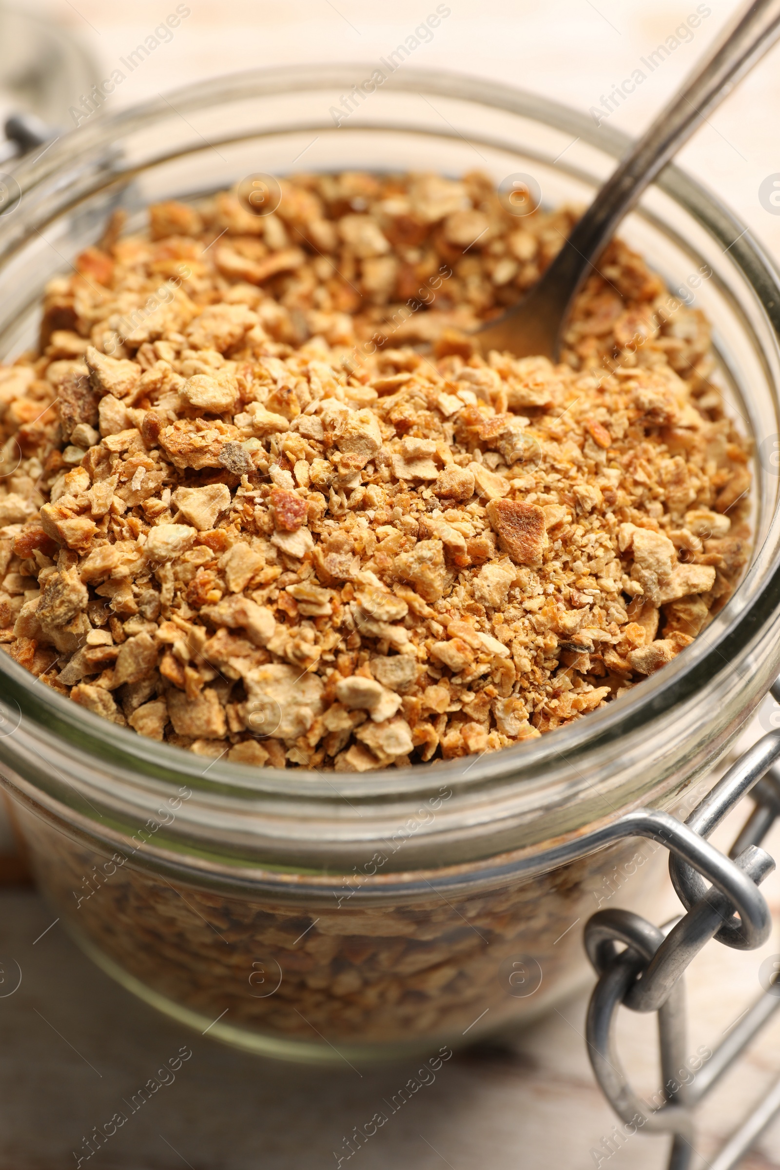 Photo of Jar of dried orange zest seasoning on white wooden table, closeup