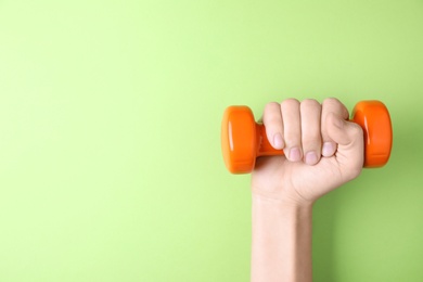 Photo of Woman holding vinyl dumbbell on color background, closeup with space for text