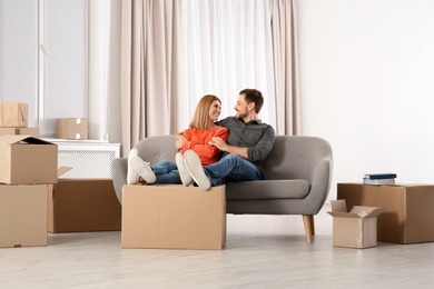 Couple resting on sofa near moving boxes in their new house