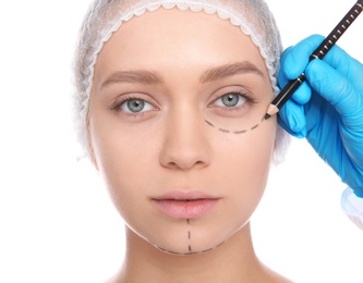 Photo of Doctor marking young woman face before cosmetic surgery on white background