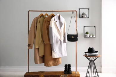 Photo of Different warm coats on rack in stylish room interior