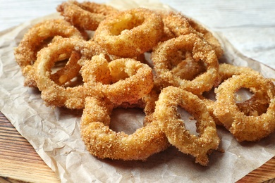 Photo of Homemade crunchy fried onion rings on wooden board, closeup