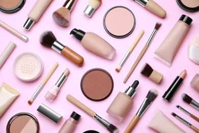 Face powders and other decorative cosmetic products on pink background, flat lay