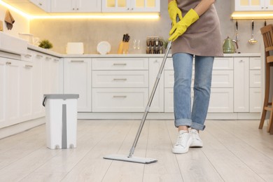 Photo of Woman cleaning floor with mop in kitchen, closeup