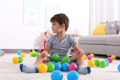 Cute little boy playing with toys on floor at home