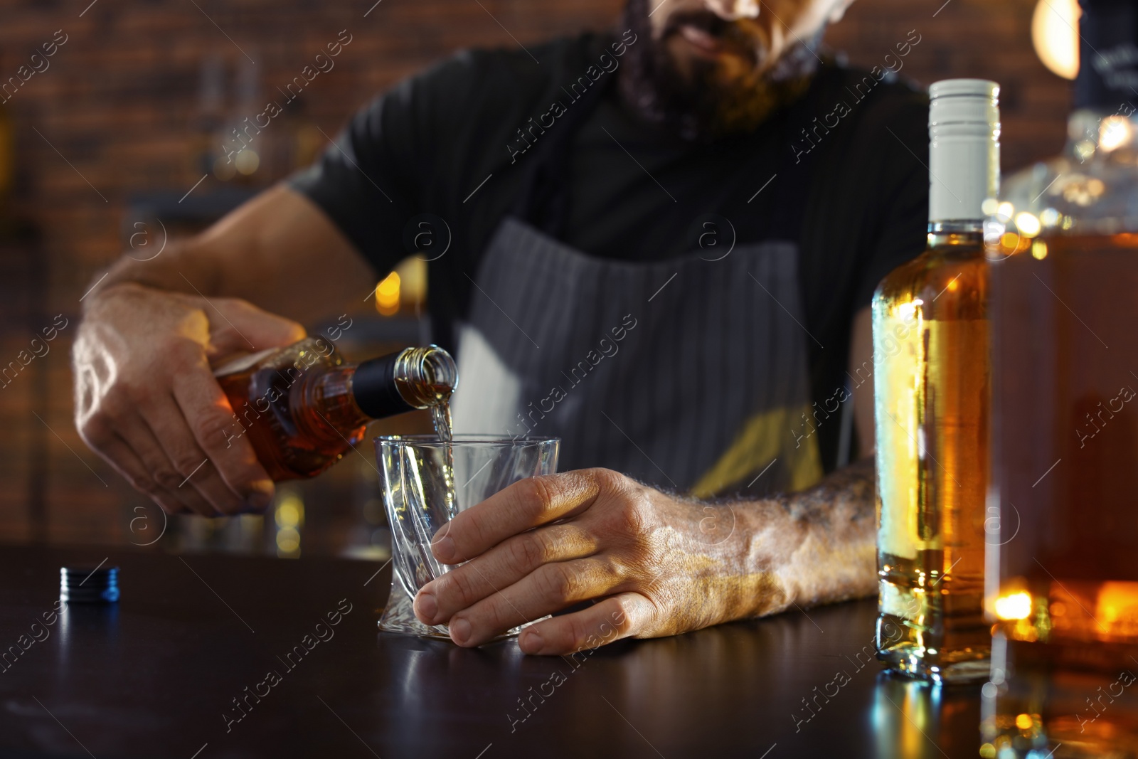 Photo of Bartender pouring whiskey into glass at counter in bar, closeup