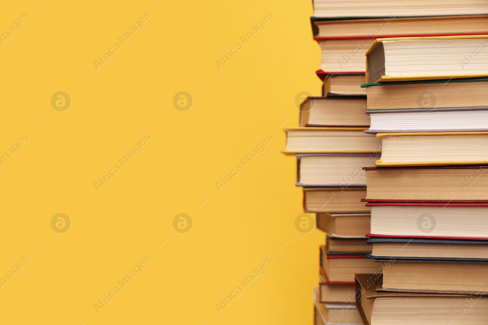 Photo of Many hardcover books on orange background, space for text. Library material