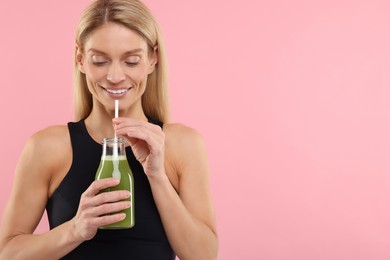 Photo of Happy woman with glass bottle of fresh celery juice on pink background. Space for text