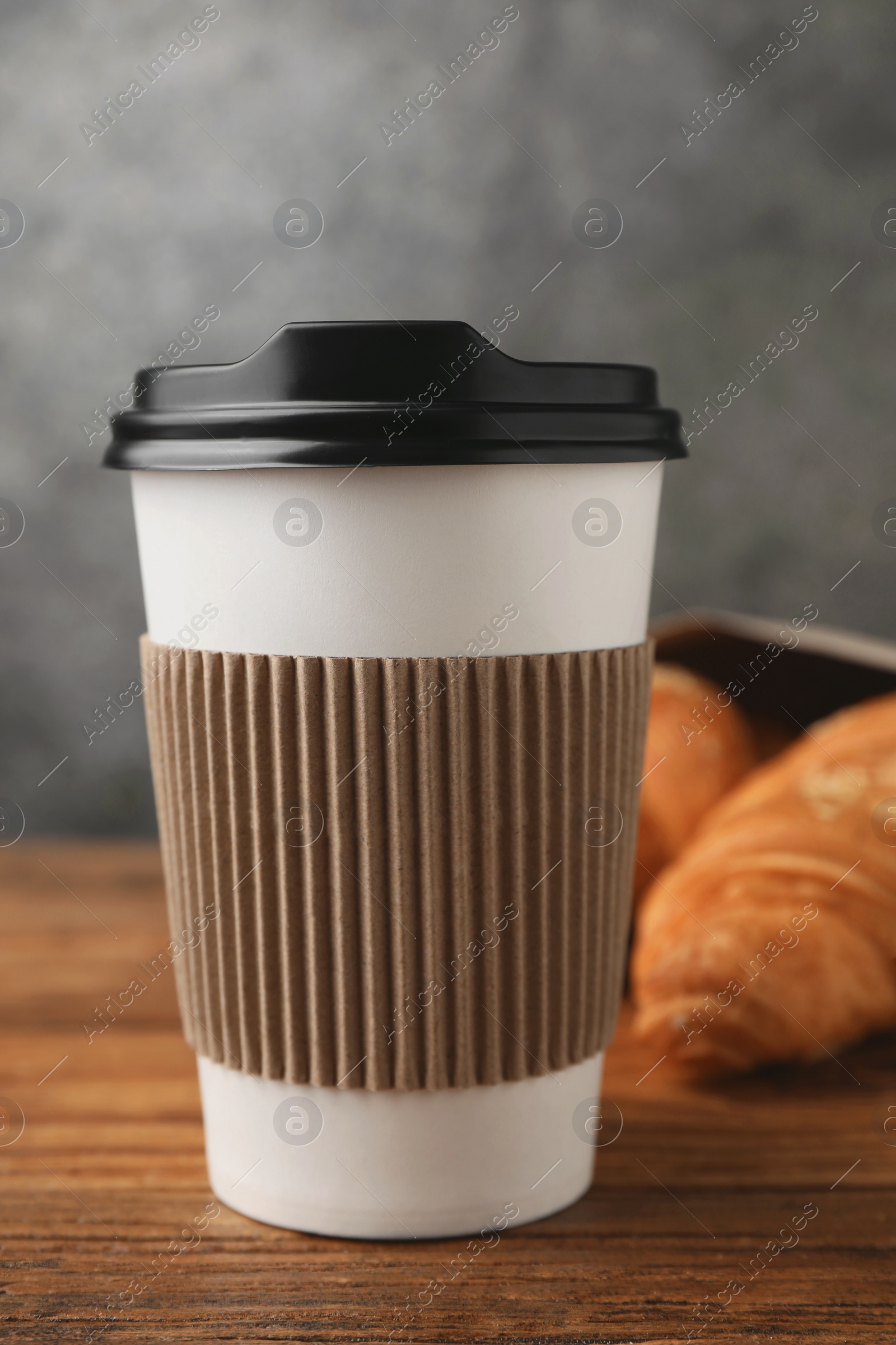 Photo of Coffee to go. Paper cup with tasty drink on wooden table, closeup