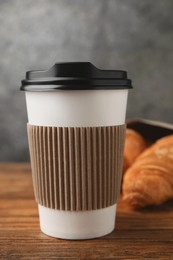 Coffee to go. Paper cup with tasty drink on wooden table, closeup