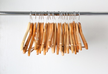 Photo of Clothes rail with wooden hangers on white background