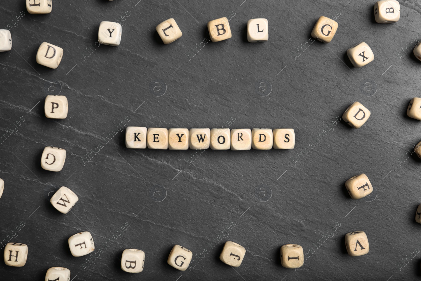 Photo of Beads with word KEYWORDS on dark grey background, flat lay