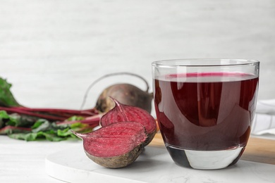 Cut beet and glass of juice on white table. Space for text