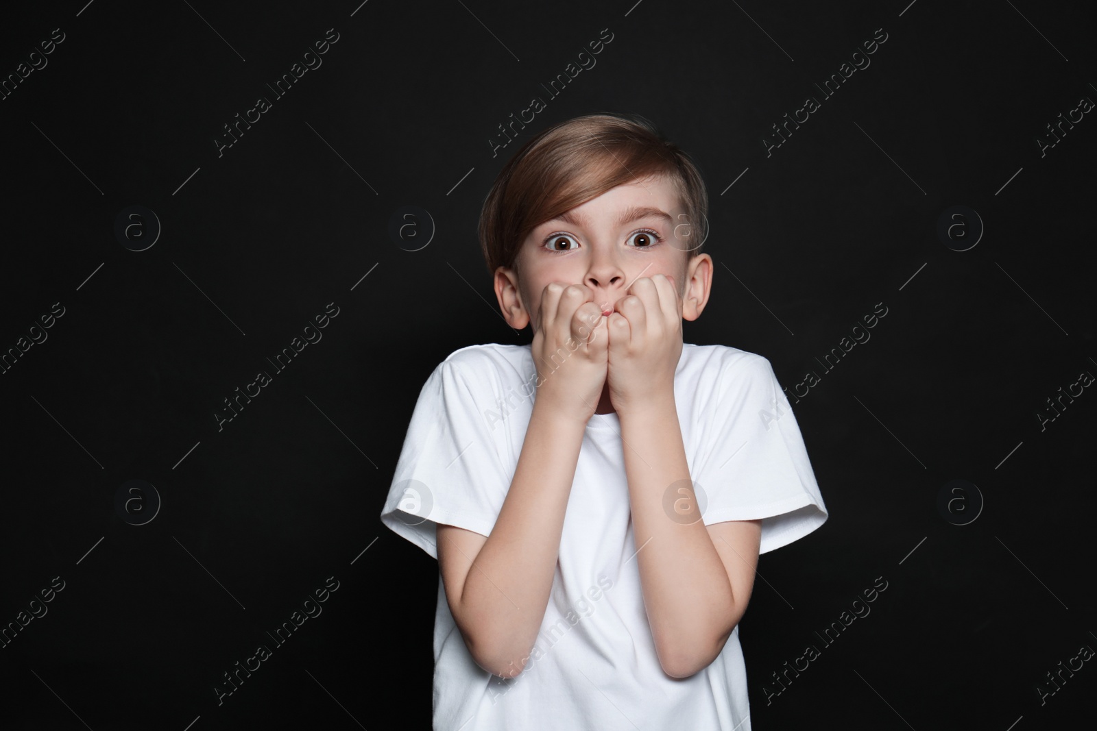 Photo of Little boy feeling fear on black background