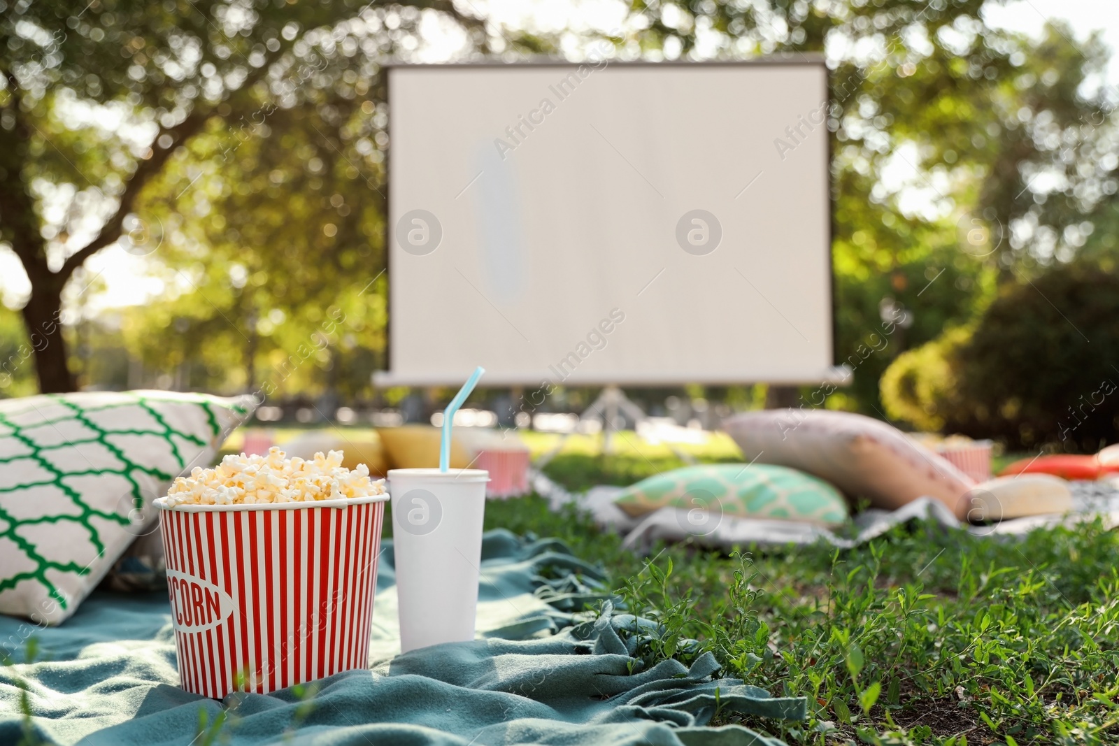 Photo of Popcorn and drink on green grass in open air cinema. Space for text