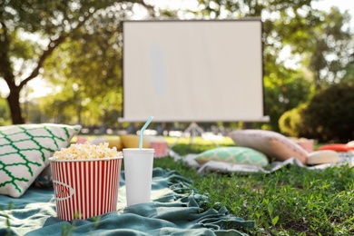 Popcorn and drink on green grass in open air cinema. Space for text