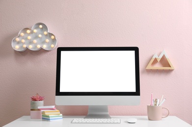 Photo of Comfortable workplace with modern computer on table near pink wall. Space for design