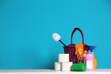 Bucket with cleaning supplies on color background