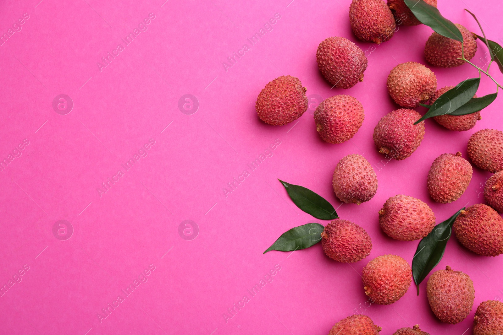 Photo of Fresh ripe lychees with leaves on pink background, flat lay. Space for text