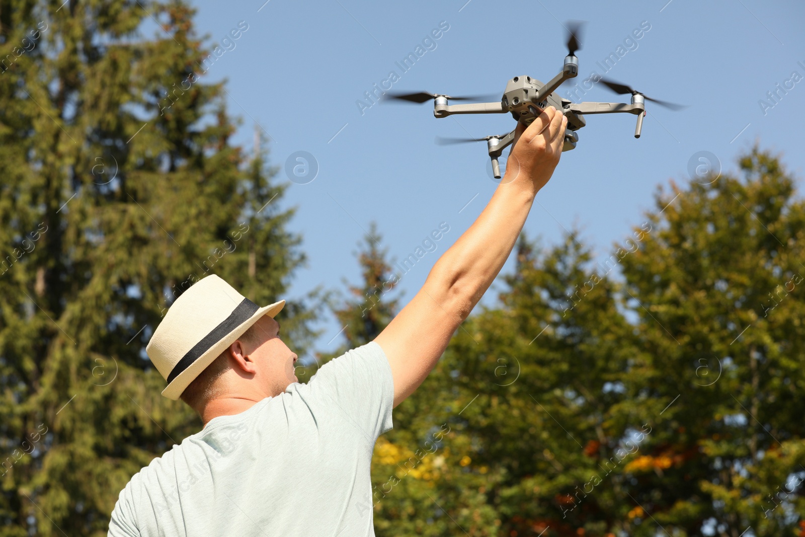 Photo of Man with drone outdoors on sunny day, back view