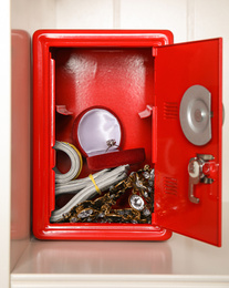 Photo of Open red steel safe with money and jewelry on shelf