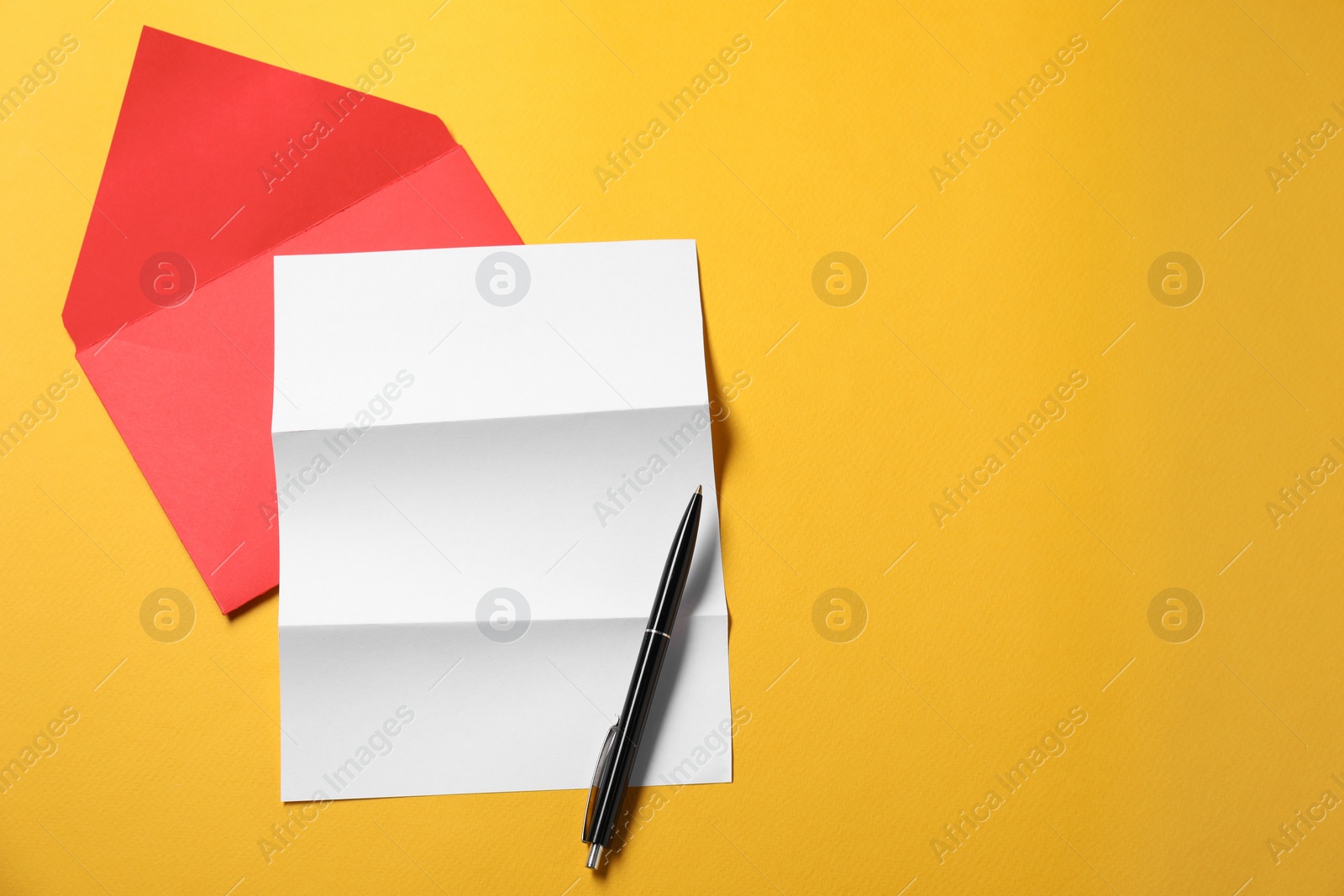 Photo of Blank sheet of paper, letter envelope and pen on orange background, top view. Space for text