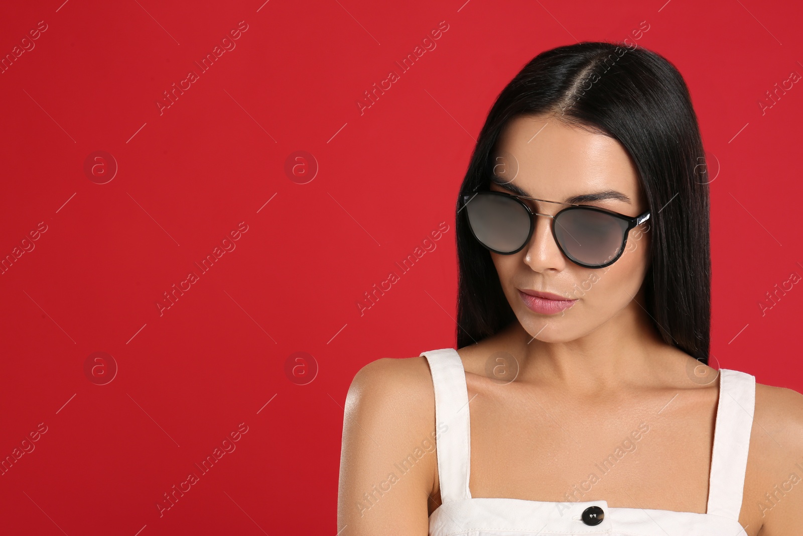 Photo of Beautiful woman wearing sunglasses on red background. Space for text