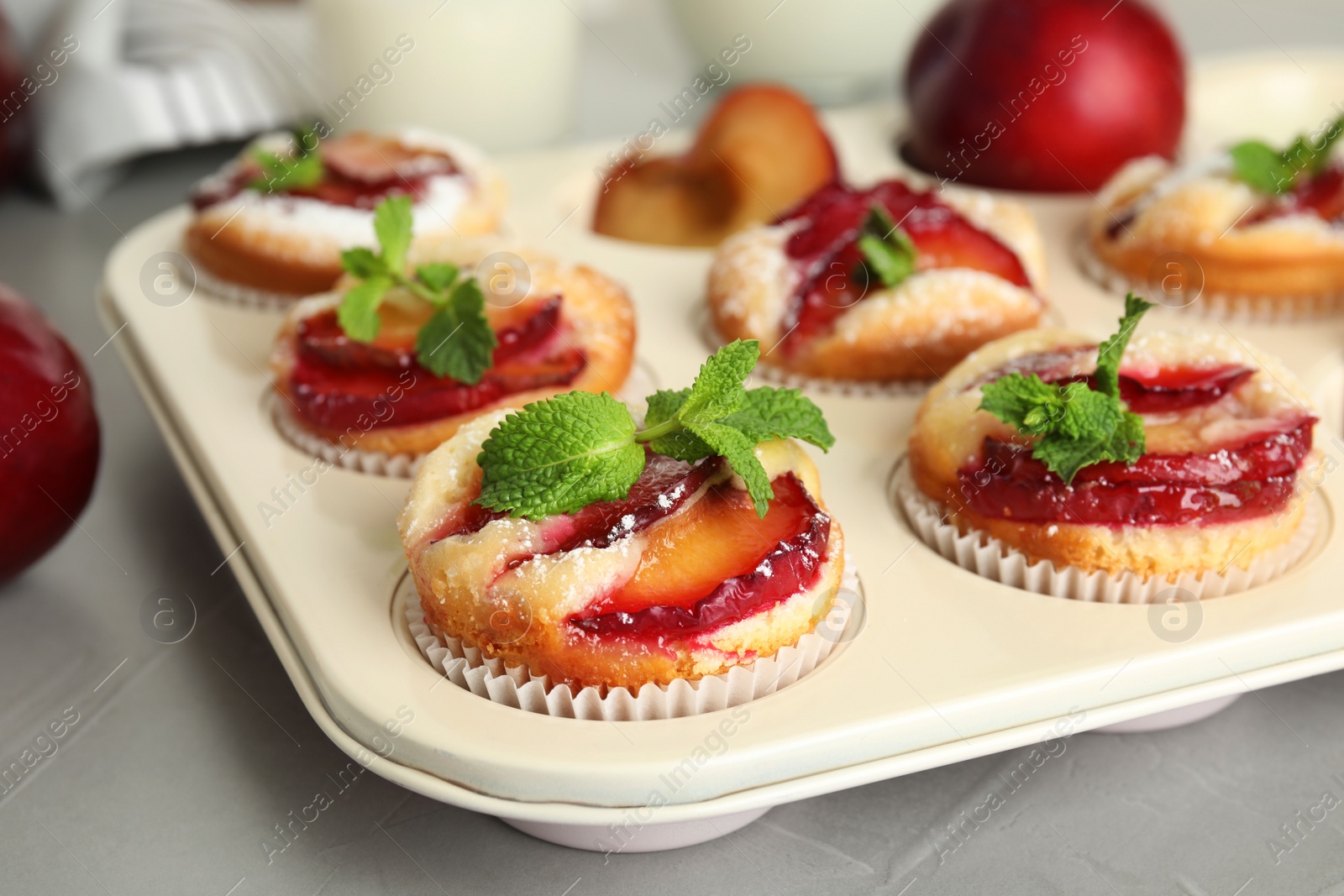 Photo of Delicious cupcakes with plums in baking pan, closeup