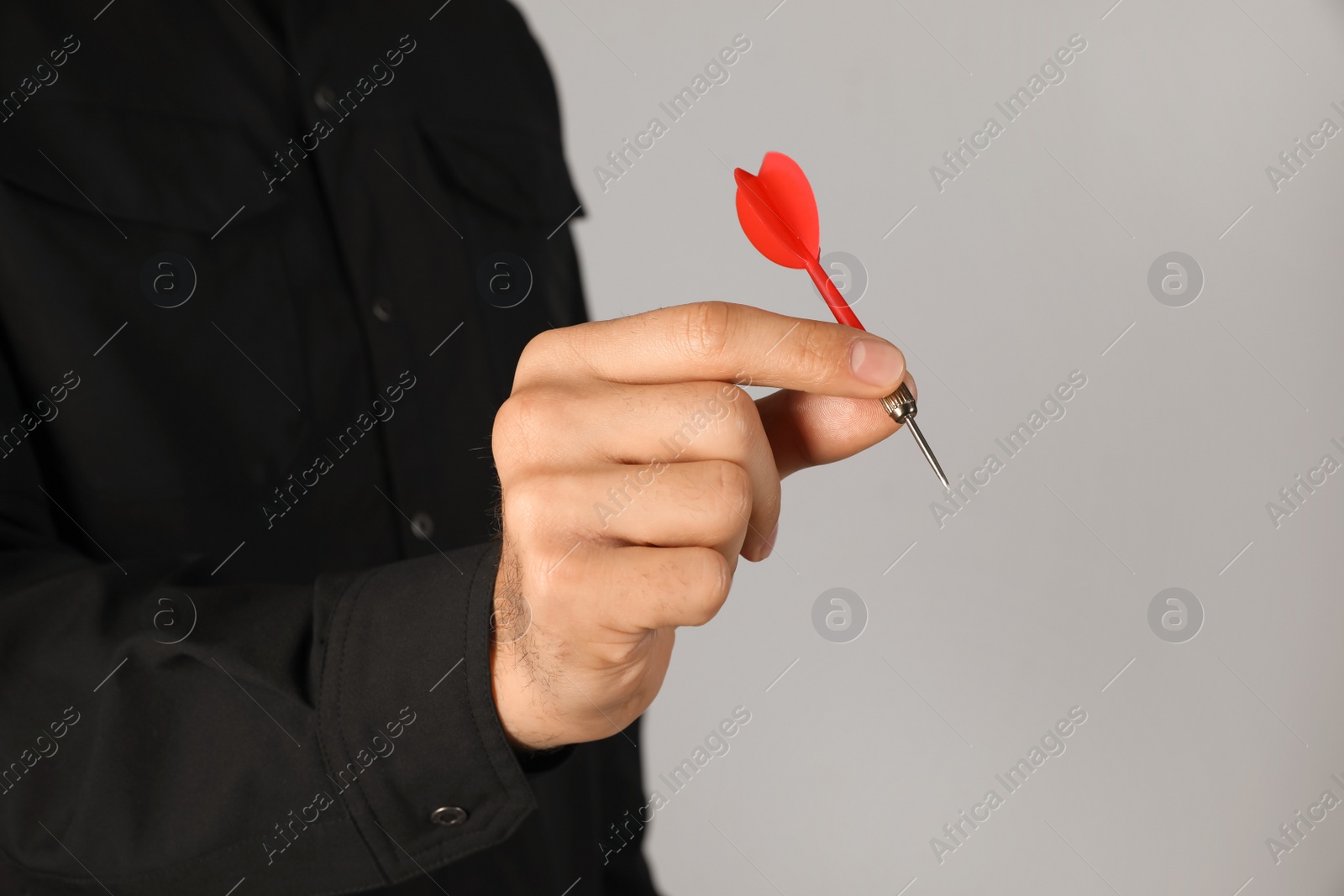 Photo of Man holding red dart on light background, closeup