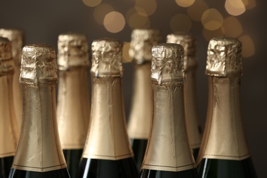 Photo of Many bottles of champagne on blurred background, closeup