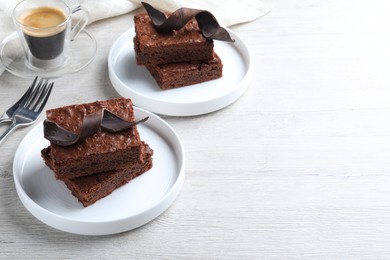 Photo of Delicious chocolate brownies served on white wooden table. Space for text