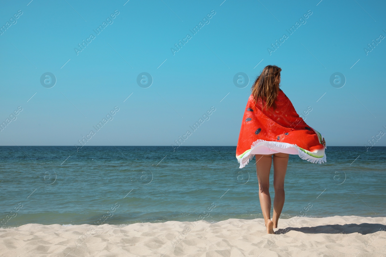 Photo of Woman with beach towel near sea on sunny day, back view