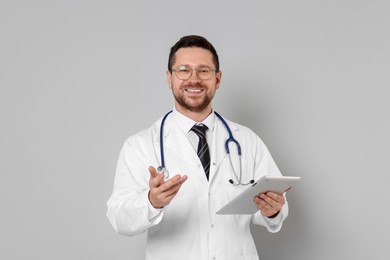 Photo of Portrait of smiling doctor with tablet on light grey background