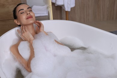 Woman taking bath with shower gel indoors
