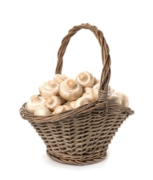 Photo of Wicker basket with fresh raw champignon mushrooms on white background