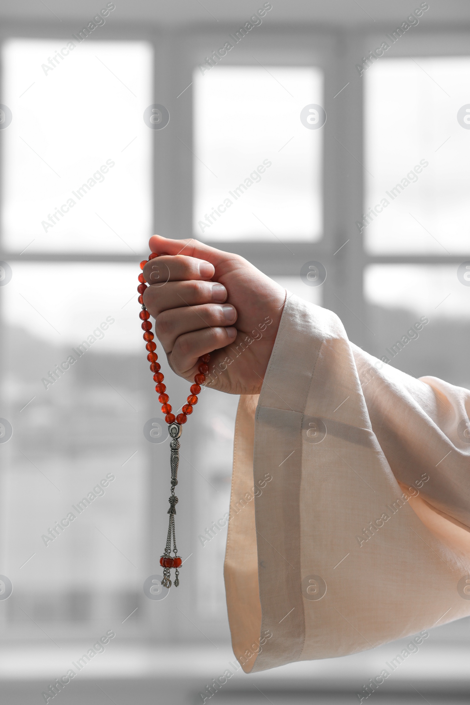 Photo of Muslim man with misbaha indoors, closeup view