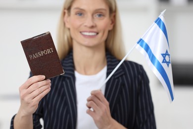 Immigration. Happy woman with passport and flag of Israel indoors, selective focus
