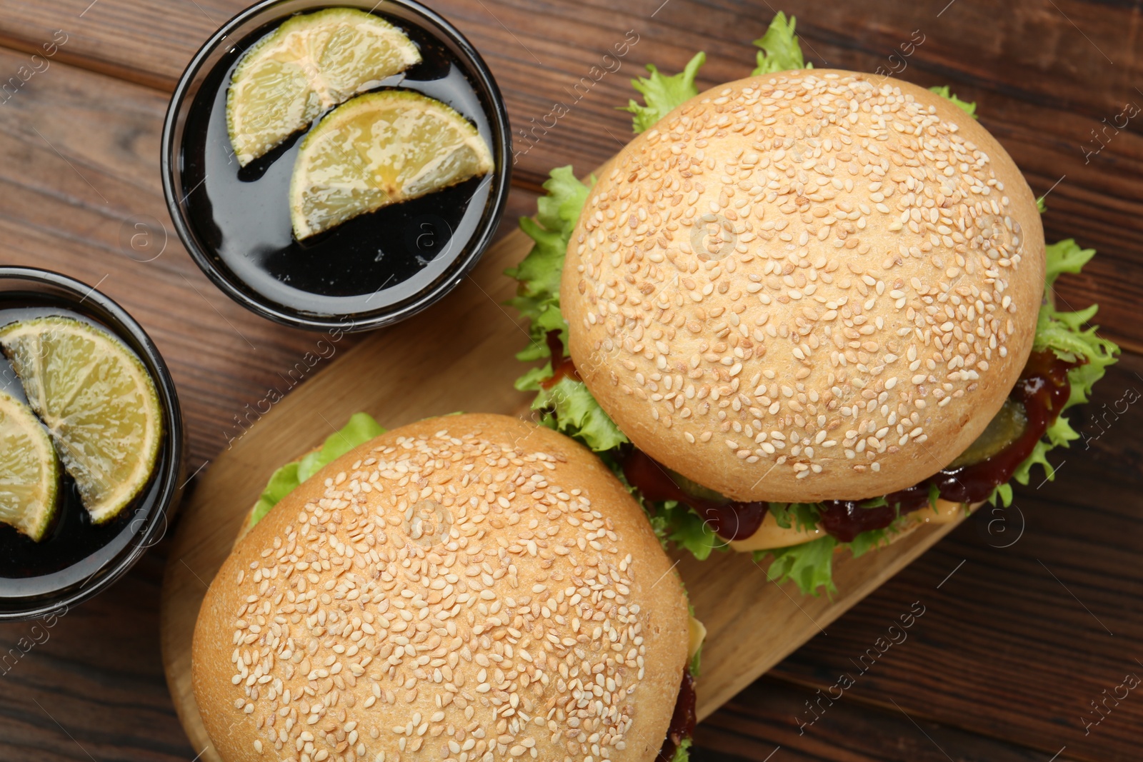 Photo of Delicious cheeseburgers and drinks on wooden table, top view