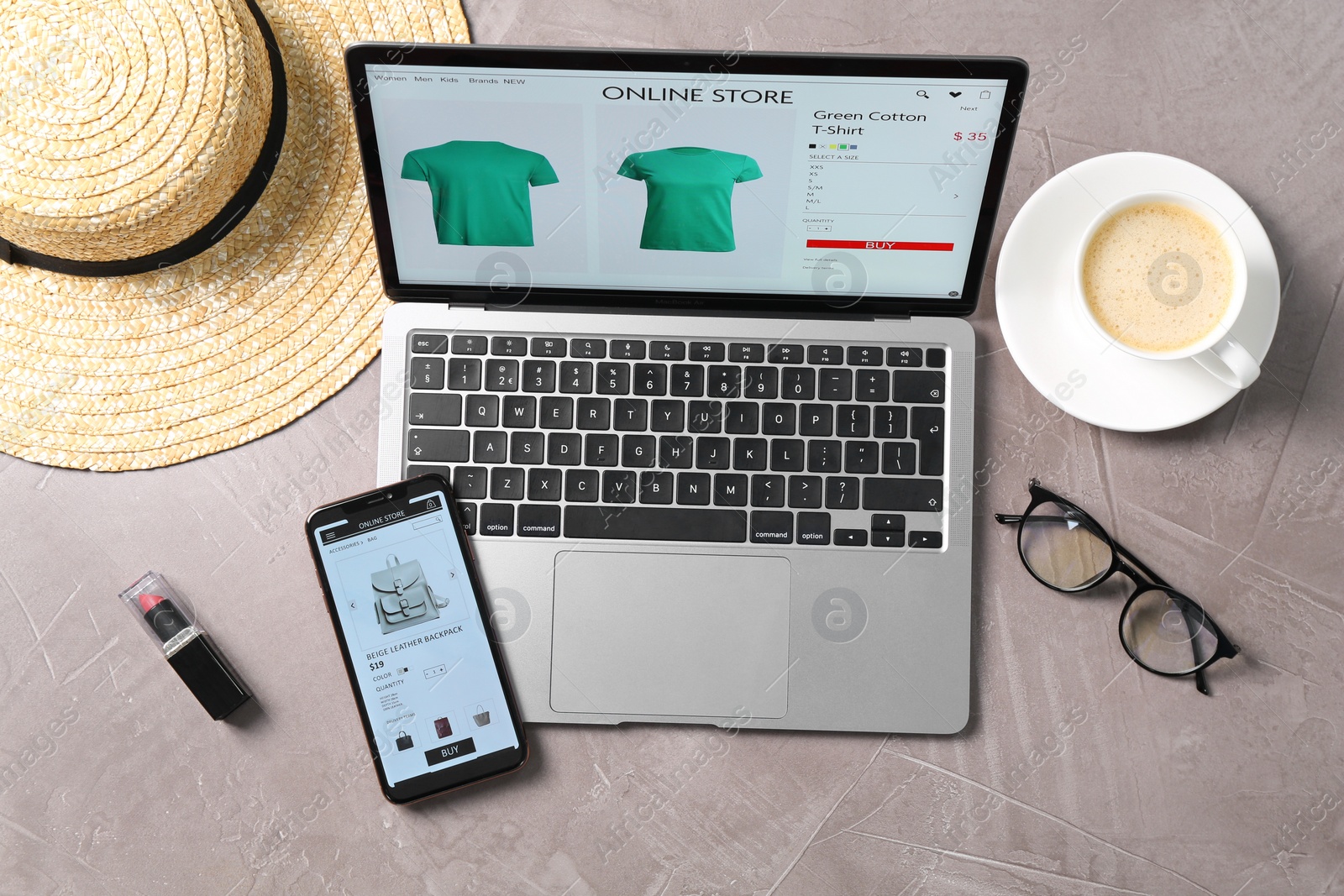 Photo of Online store website on laptop screen. Computer, smartphone, coffee and accessories on grey table, flat lay