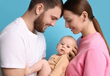 Photo of Happy family. Parents with their cute baby on light blue background