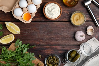 Photo of Tasty tartar sauce and ingredients on wooden table, flat lay. Space for text