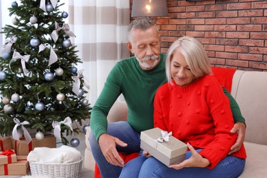 Mature couple with Christmas gift box at home