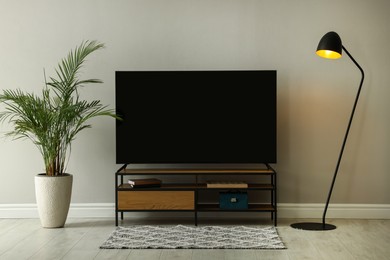 Stylish wide TV set on stand in room
